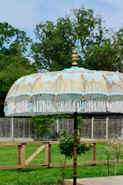 Close-up of white tassel fringe and mother of pearl shell heart detail on blue garden parasol