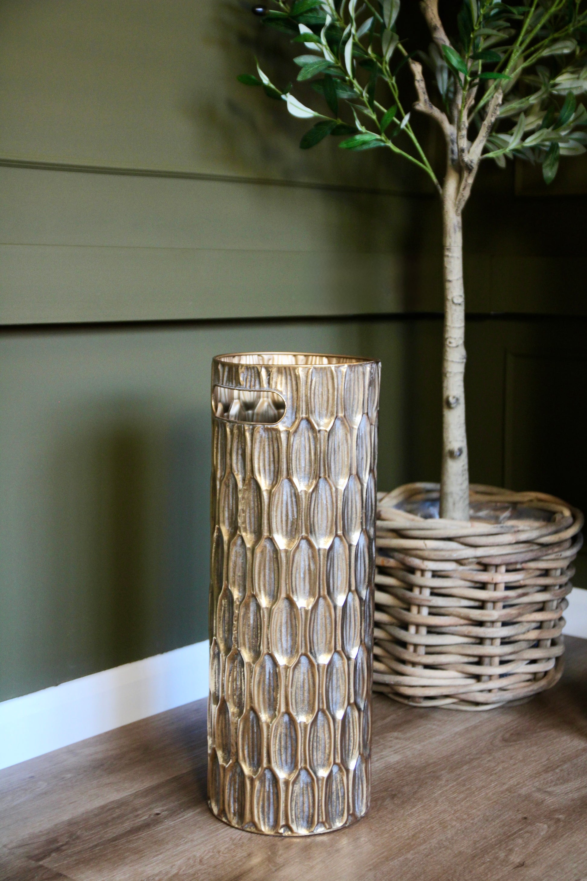 Tall gold umbrella stand with a richly textured decorative surface and cut-out handles.